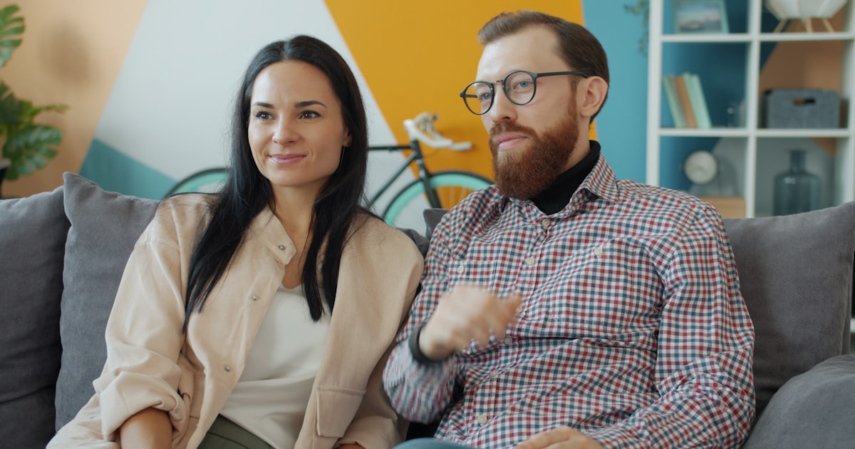 Una pareja sentada en el sillón de su casa, conversando